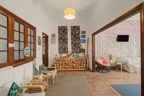 A cozy living room with a wooden cabinet, a sofa, a chair, and a television. - Triple Room with External Private Bathroom (Las Palmas de Gran Canaria)