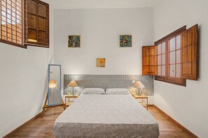 Ein Schlafzimmer mit einem Bett, zwei Nachttischen, einem Spiegel und Bildern an den Wänden.