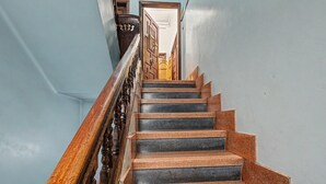 Een trap met houten leuning en stenen treden die leiden naar een geopende deur.