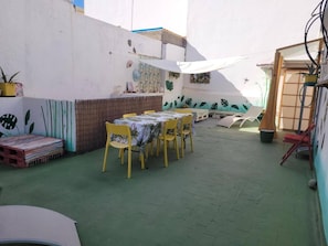 Eine Terrasse mit Tisch und Stühlen, eine kleine Sitzecke und eine Wand mit Blattform-Verzierung.