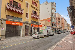 Una strada con auto parcheggiate e una fila di edifici con negozi.