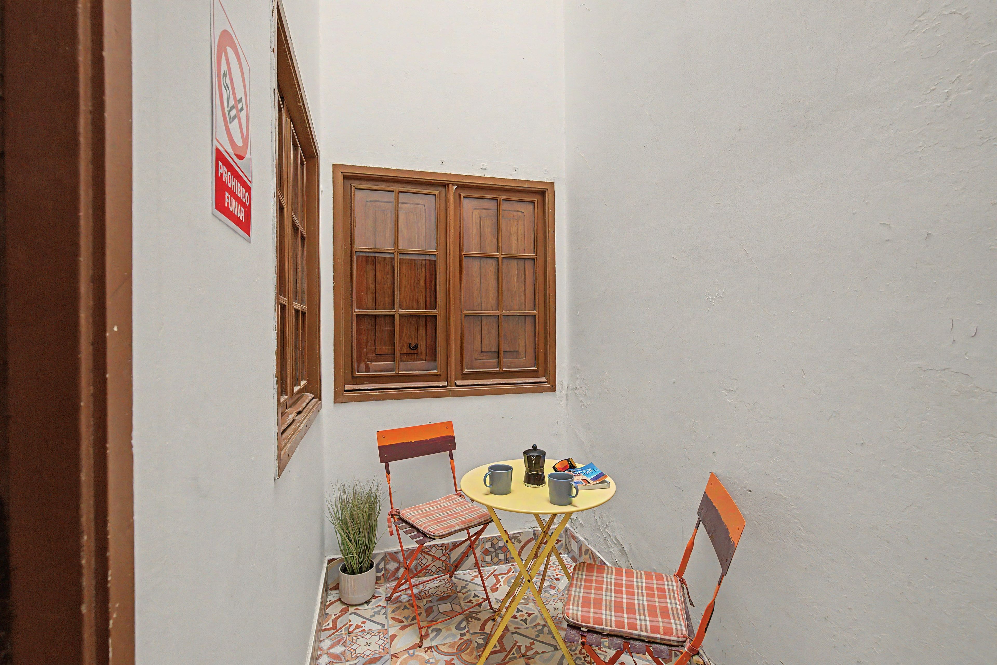 A small outdoor seating area with a table, chairs, and a window.