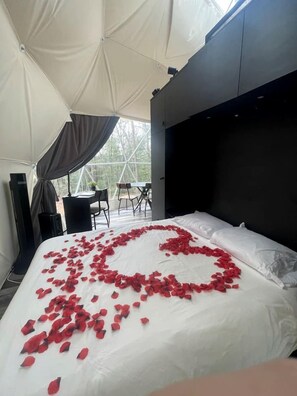 A tented room with a bed, a desk, and a chair.