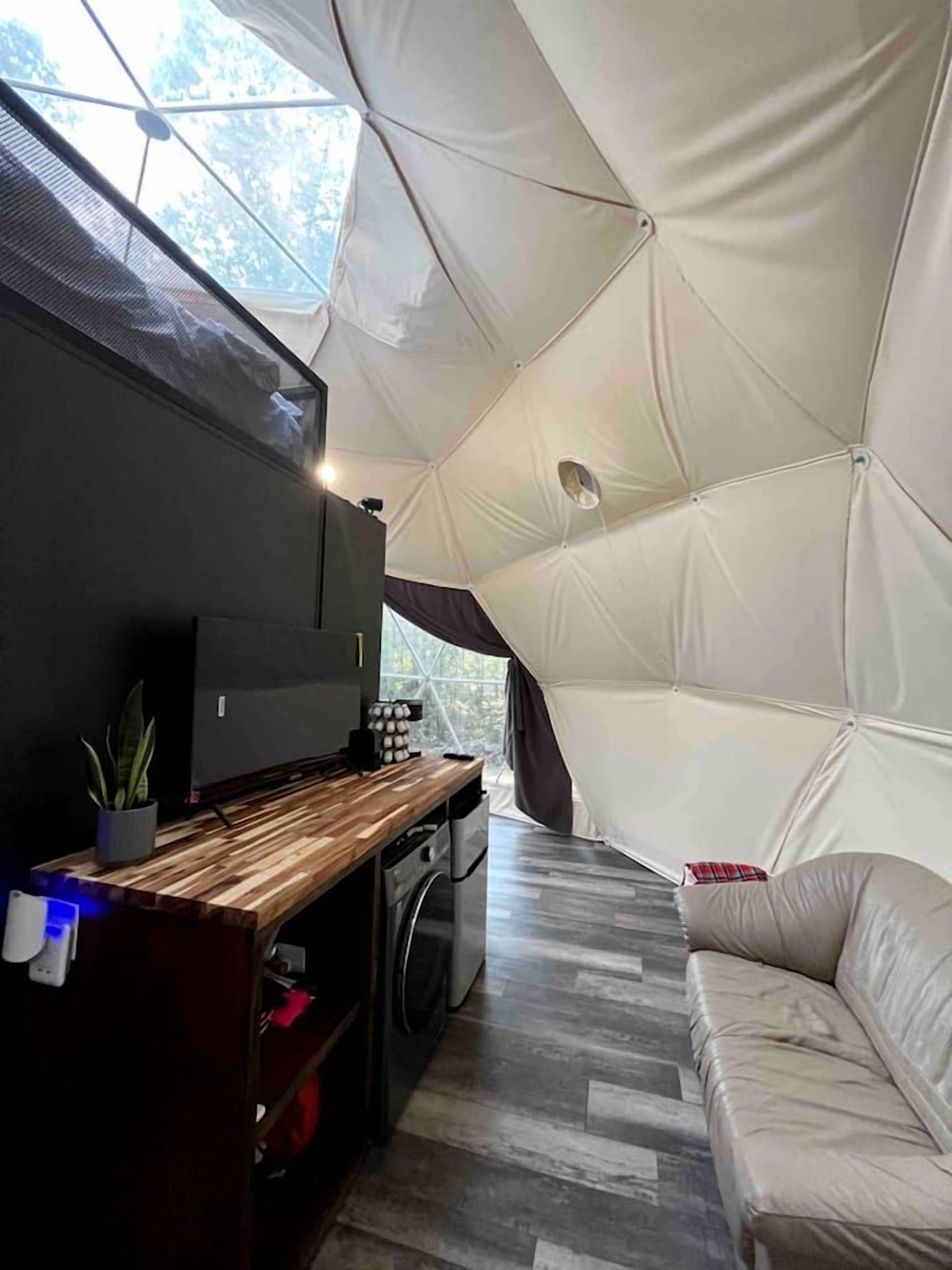 A tent with a kitchen area, a sofa, and a TV.
