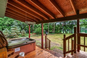 Eine Holzterrasse mit Whirlpool, einer Holztreppe und einem Schild, das zum Strand weist.