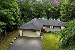 Einbungalow mit Garage, umgeben von dichten Bäumen.