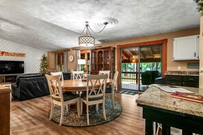 A spacious living area with a dining table, chairs, a fireplace, and a television. - Pet Friendly Lakefront Cottage with Hot-tub in Johannesburg, Michigan (Johannesburgo)