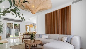 Een moderne woonkamer met een hoekbank, een eethoek met een tafel en stoelen, en een groot raam met uitzicht op groen.