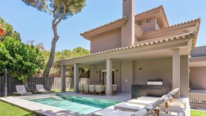 Een modern huis met een zwembad, terras en overdekte patio.