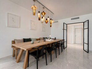 A modern dining area with a wooden table, black chairs, and pendant lighting. - Apartment 'Beachside  San-Pedro' with Mountain View, Wi-Fi and Air Conditioning (Marbella)