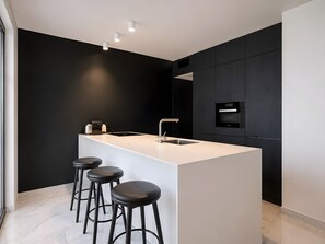 A modern kitchen with a central island, bar stools, a built-in oven, and pendant lighting. - Apartment 'Beachside  San-Pedro' with Mountain View, Wi-Fi and Air Conditioning (Marbella)