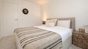Ein Schlafzimmer mit Bett, Wanduhr, Nachttisch mit Lampe und einer Wanddekoration.