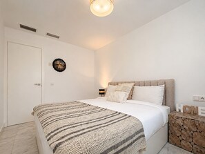 A bedroom with a bed, a wall clock, a bedside table with a lamp, and a decorative wall piece. - Apartment 'Beachside  San-Pedro' with Mountain View, Wi-Fi and Air Conditioning (Marbella)