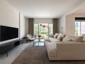 A modern living room with a large flat-screen TV, a sofa, a coffee table, and a chair. - Apartment 'Beachside  San-Pedro' with Mountain View, Wi-Fi and Air Conditioning (Marbella)