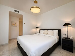 A modern bedroom with a large bed, two bedside tables with lamps, a ceiling light, a wall-mounted air vent, and a door leading to another room. - Apartment 'Beachside  San-Pedro' with Mountain View, Wi-Fi and Air Conditioning (Marbella)