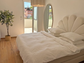 Un dormitorio con cama, una planta en maceta, un espejo y vistas al exterior.