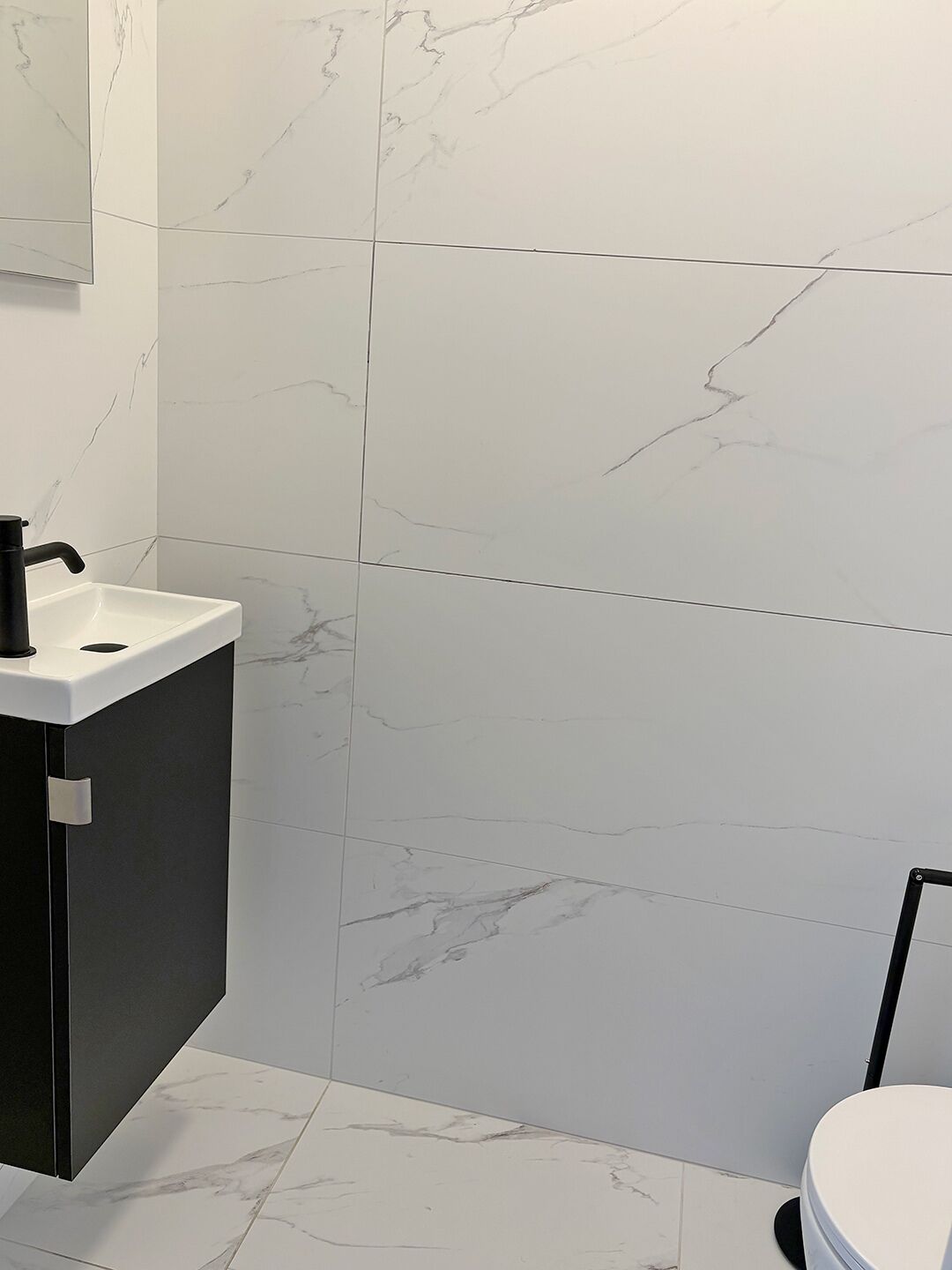 A bathroom with a white sink, black cabinet, and a toilet.