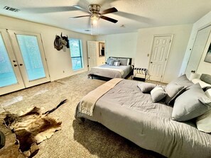 A bedroom with a bed, a ceiling fan, a rug, and a mounted animal head. - Nature Lover’s Dream with Expansive Tiered Deck Spaces in Garfield, Arkansas (Garfield)