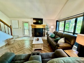 Una sala de estar con chimenea, un sofá, una mesa de centro y una televisión.