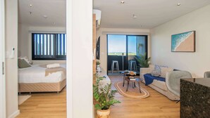 Een modern appartement met een bed, een slaapbank, een eettafel en een balkon met uitzicht.