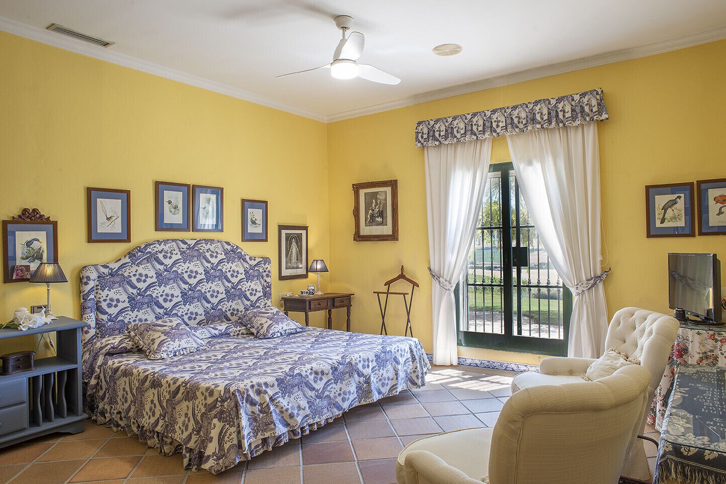 Une chambre à coucher avec un lit, une chaise, un bureau et une fenêtre avec des rideaux.