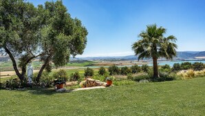 A grassy landscape with a statue, trees, and a view of distant hills and water. - Charming and Spacious Family Villa - Cortijo Sierra y Lago (Arcos de la Frontera)