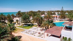 Resort com piscina, palmeiras e acesso à praia.