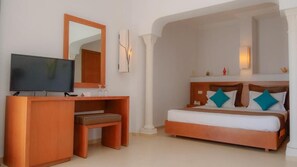 A hotel room with a bed, a TV, a desk, and a mirror. - GOLF BEACH  (Aghir)