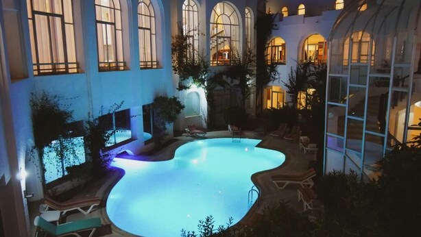 Piscina com espreguiçadeiras, janelas em arco e estrutura de estufa.