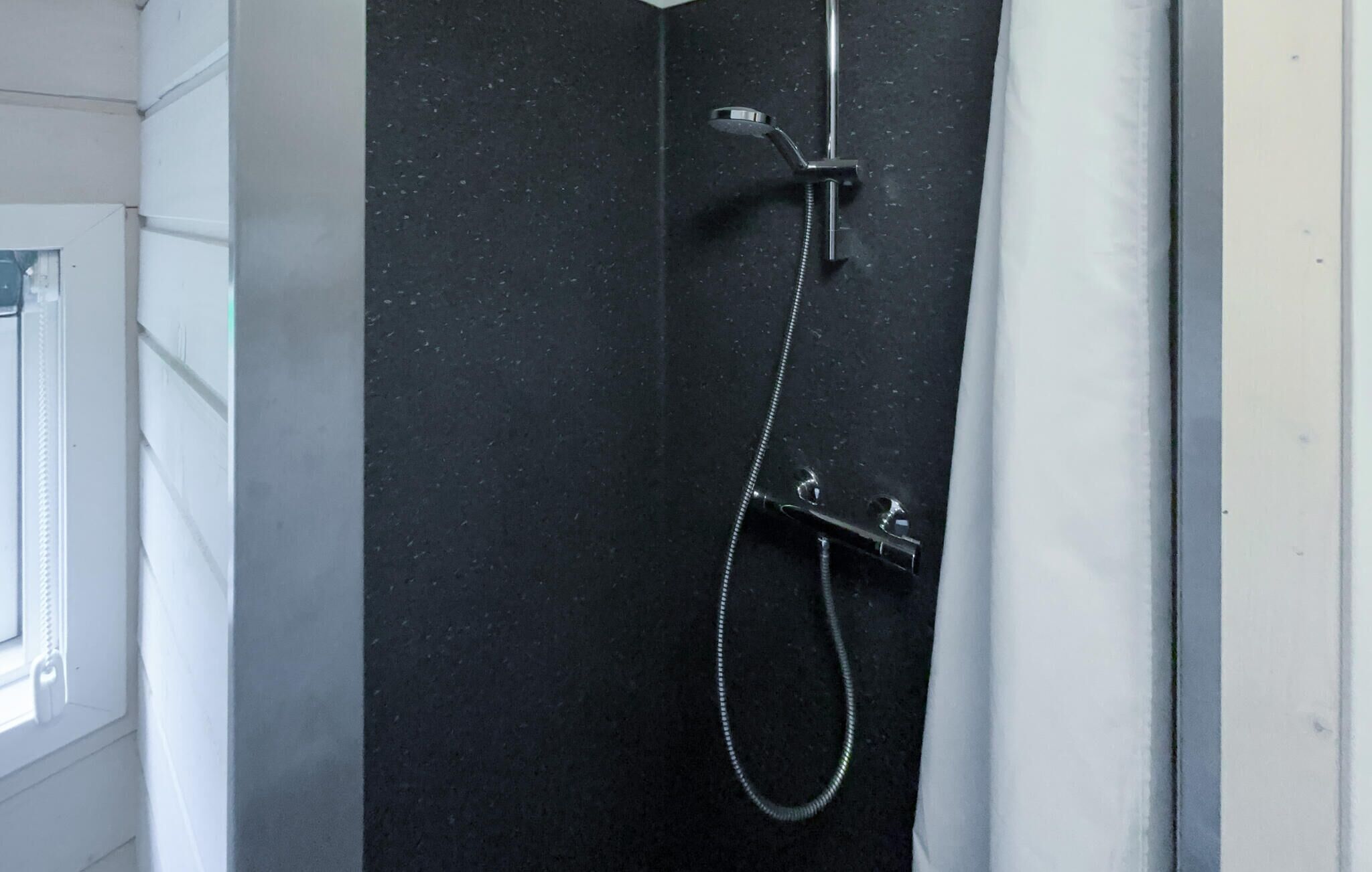 Eine Dusche mit Duschbrause und Wandarmatur.