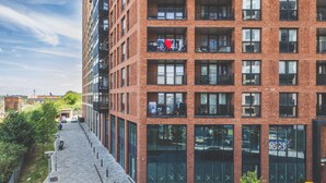 Un immeuble à plusieurs étages, doté d’une façade en briques, de grandes fenêtres et d’une promenade piétonne.