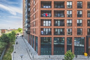 A multi-story building with a brick facade, large windows, and a pedestrian walkway. - Modern 1BDR Flat Near Elizabeth Line and Heathrow (Greater London)