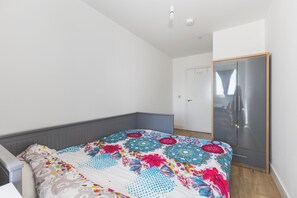 A bedroom with a bed, a wardrobe, and a door. - Modern 1BDR Flat Near Elizabeth Line and Heathrow (Greater London)