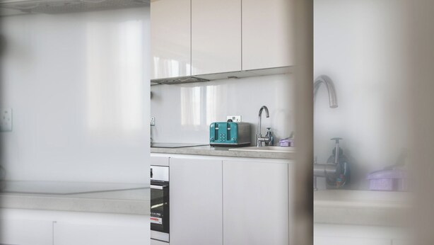 Une cuisine moderne avec des meubles blancs, un évier en acier inoxydable et un grille-pain de couleur turquoise.