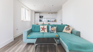 Un salon moderne avec un canapé de couleur turquoise, une table basse noire et des coussins décoratifs.