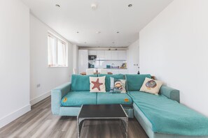 A modern living room with a teal sofa, a black coffee table, and decorative pillows. - Modern 1BDR Flat Near Elizabeth Line and Heathrow (Greater London)