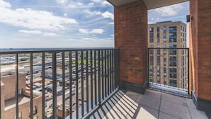 Un balcon donnant sur un parking et un immeuble.