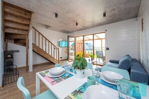 Ein Essbereich mit Tisch für vier Personen, einer Couch, einer Treppe und einem Fernseher an der Wand.