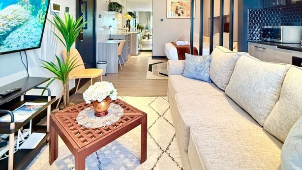 A modern living room with a sofa, coffee table, TV, and a kitchen in the background. - Nairobi, Kenya. Spacious & Elegant studio Apartment +Gym+Pool+Rooftop Restaurant (Nairobi)