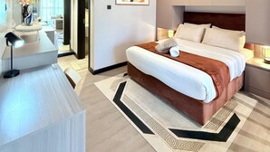 A modern hotel room with a large bed, bedside tables, a desk, and a painting on the wall. - Nairobi, Kenya. Spacious & Elegant studio Apartment +Gym+Pool+Rooftop Restaurant (Nairobi)