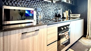 A modern kitchen with a microwave, oven, and a large window. - Nairobi, Kenya. Spacious & Elegant studio Apartment +Gym+Pool+Rooftop Restaurant (Nairobi)