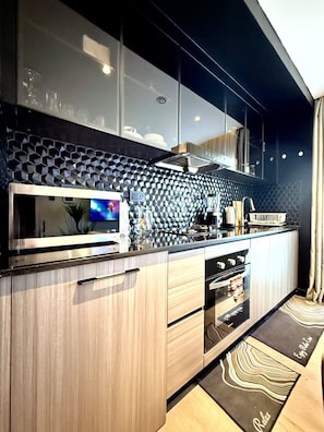A modern kitchen with a microwave, oven, and a large window. - Nairobi, Kenya. Spacious & Elegant studio Apartment +Gym+Pool+Rooftop Restaurant (Nairobi)