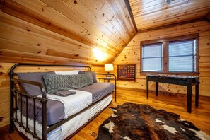 A cozy room with a bed, a table, and a window. - Luxury Cabin with Hot Tub & Game Room Retreat in Broken Bow, Oklahoma (Broken Bow)