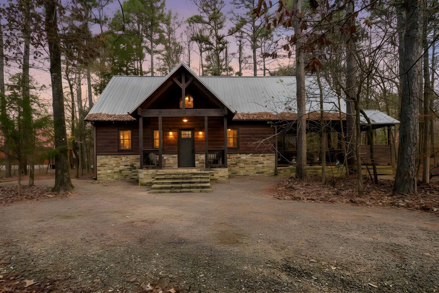 A rustic cabin with a stone foundation, wooden exterior, and a metal roof.