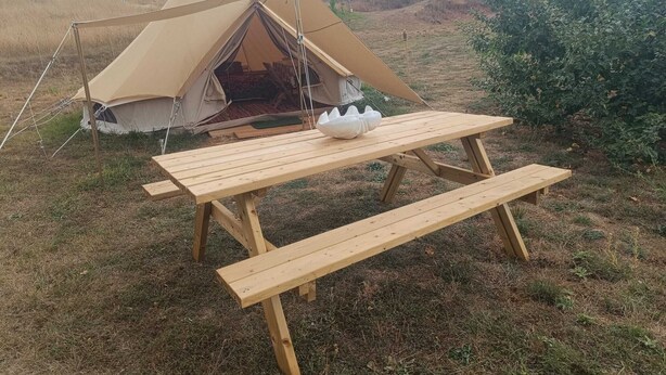 Una carpa con una mesa de picnic en un campo cubierto de hierba.