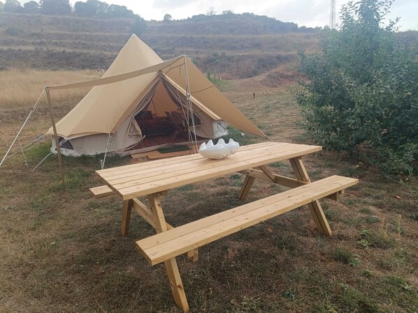Una carpa con una mesa de picnic en un campo cubierto de hierba.