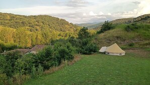 Una tienda de campaña en un campo con colinas al fondo.