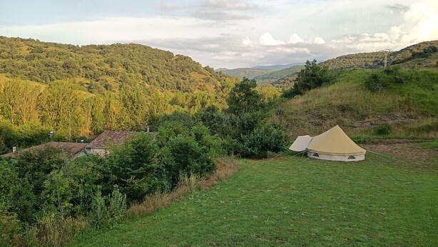 A tent in a grassy field with hills in the background. - Astial Ezquerra Experience – Nature with Charm (Sierra de la Demanda)
