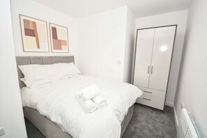 Ein Schlafzimmer mit einem Bett, einem Kleiderschrank und zwei gerahmten Bildern an der Wand.