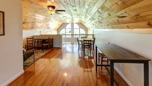 A loft-style room with a sloped ceiling, wooden beams, a dining table, chairs, and a small seating area. - Serene Getaway on Private Land with Panoramic Views in Walton, New York (Walton)